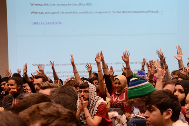 Students who support NU Divest raise their hands to speak during the debates at the Feb. 19, 2015 ASG meeting.